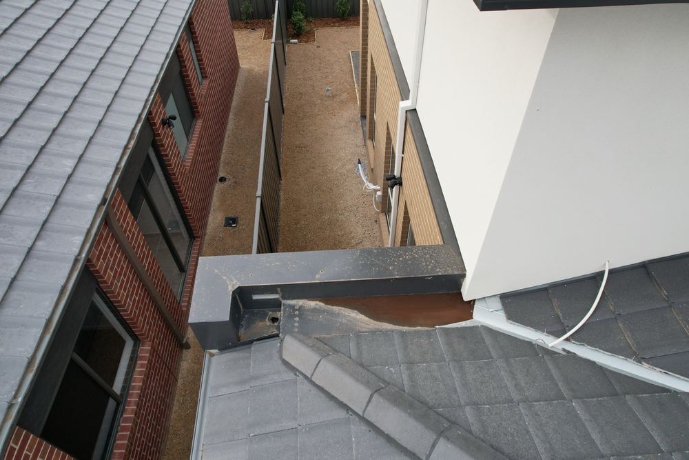 Box gutter still holding water on a dry day, showing poor fall, found during a pre-handover inspection in Berwick